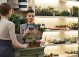 Can VoIP Improve Customer Support for Small Businesses? A woman behind a counter in a nursery helping a customer while holding a plant