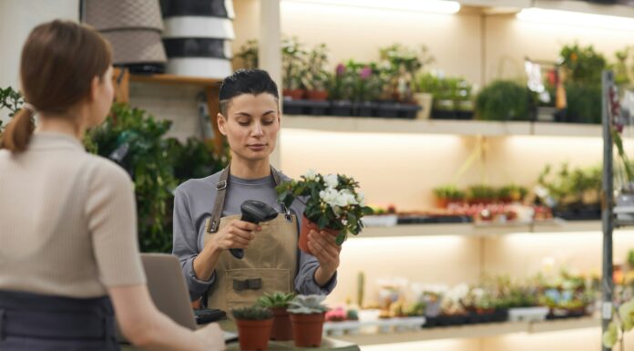Can VoIP Improve Customer Support for Small Businesses? A woman behind a counter in a nursery helping a customer while holding a plant