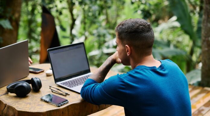 How Full Fibre Could Transform Remote Work for UK Residents A man sitting at a wooden table outside working on his laptop