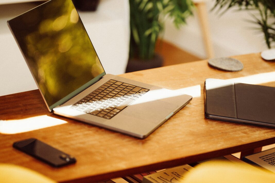 A photo of a laptop sitting on a wooden desk with a beam of sunlight shining over it