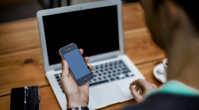What Are the Pros and Cons of Prepaid Mobile Broadband Plans A man sitting at a wooden table with his laptop and phone