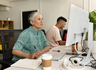 What is The Fastest Internet Speed in the UK? A woman sitting at her desk looking at her computer screen while writing in a notebook