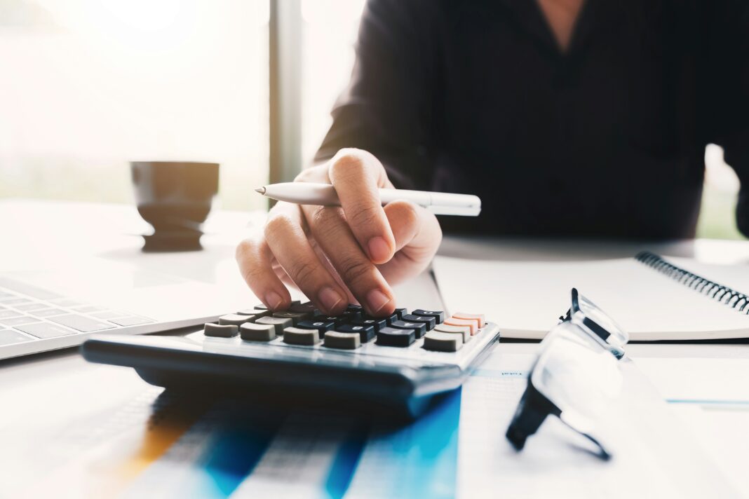 woman-typing-on-a-calculator-with-a-pen-in-her-hand