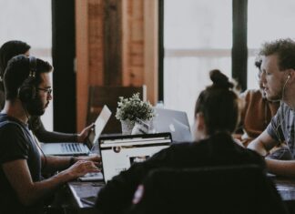 Why VoIP Should Be Part of Your Company’s Digital Communication Policy people-working-shared-co-working-desk-with-quality-headsets