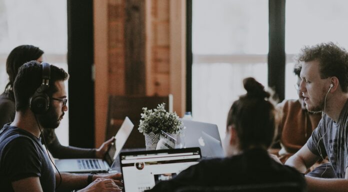Why VoIP Should Be Part of Your Company’s Digital Communication Policy people-working-shared-co-working-desk-with-quality-headsets