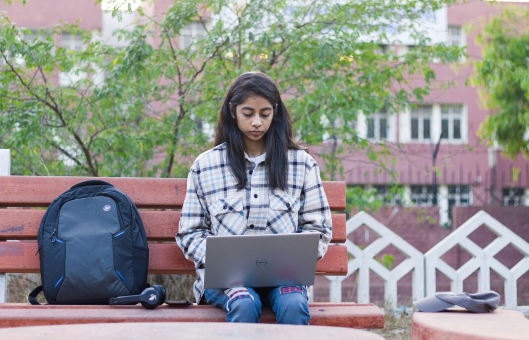 student-working-outdoors-on-park-bench