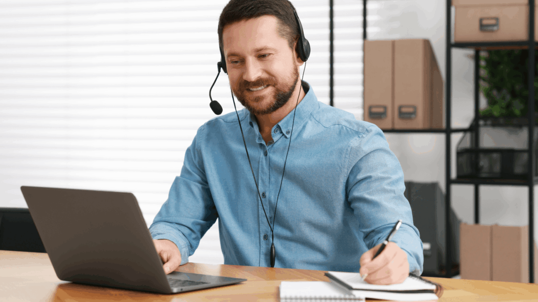 man-working-desk-writing-using-headset-through-voip